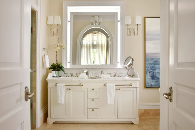 A bathroom vanity with orchids and a lit mirror
