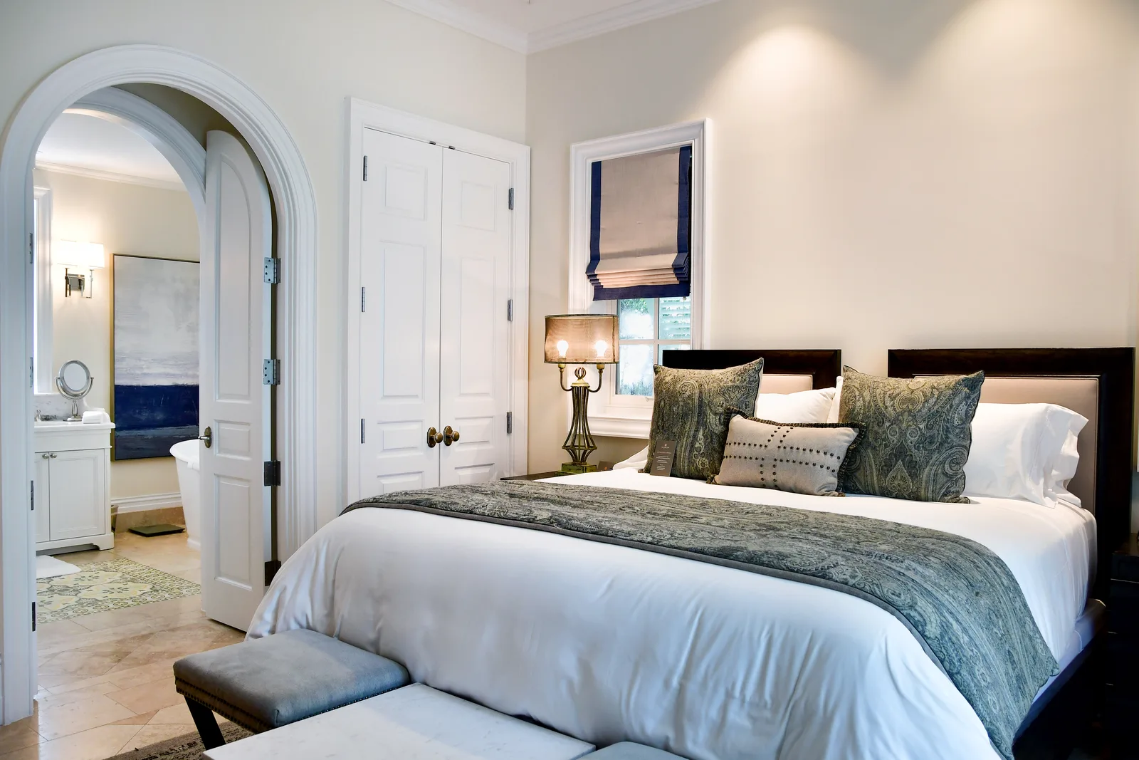 A guest bedroom with grey throw and an arched doorway