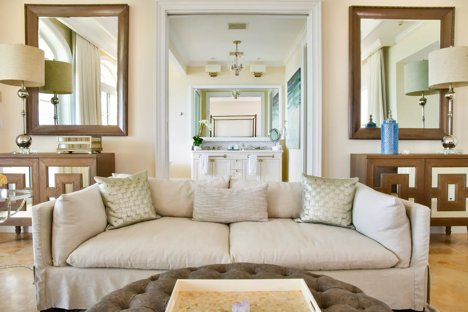 A sitting room with a linen sofa and mirrored consoles