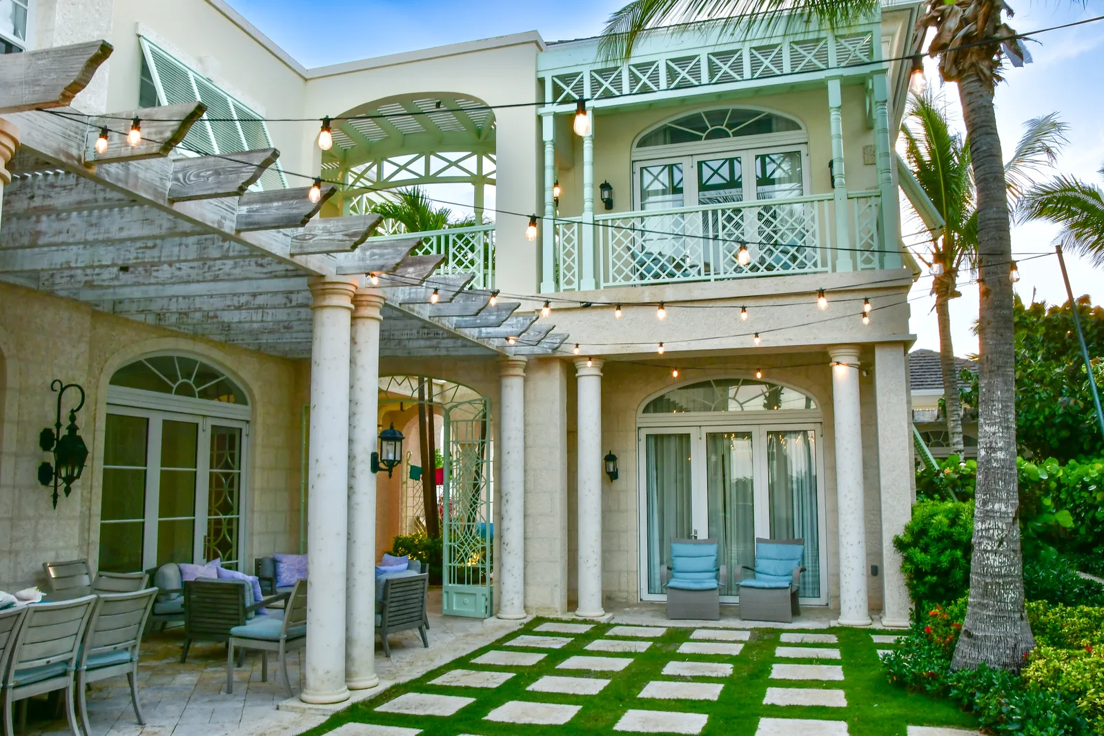 The villa at dusk, lights on along the pergola