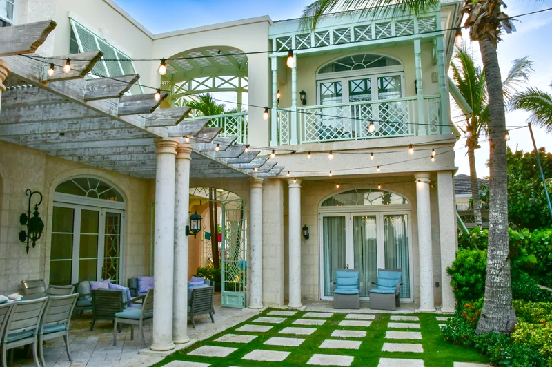 The villa at dusk, lights on along the pergola