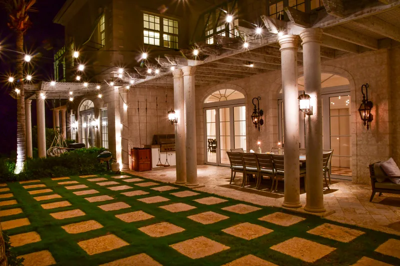 The courtyard at night, string lights over the lawn and the outdoor dining table